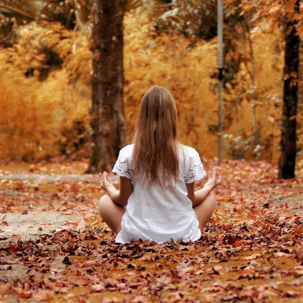 Femeie meditând în pădure toamna